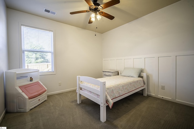 bedroom featuring visible vents, a wainscoted wall, a ceiling fan, carpet, and a decorative wall