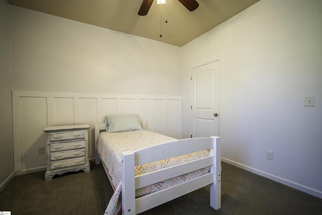 bedroom featuring a decorative wall, dark carpet, and ceiling fan