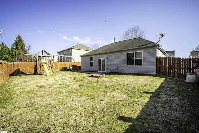 rear view of property with a playground, a yard, and a fenced backyard