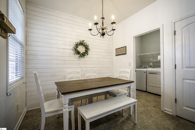 dining area with washer and dryer, wood walls, and an inviting chandelier