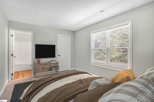 carpeted bedroom with visible vents, a textured ceiling, and baseboards