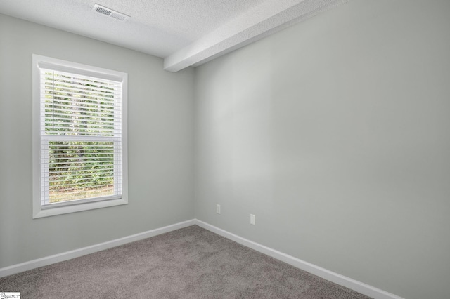 spare room featuring visible vents, carpet flooring, a textured ceiling, and baseboards