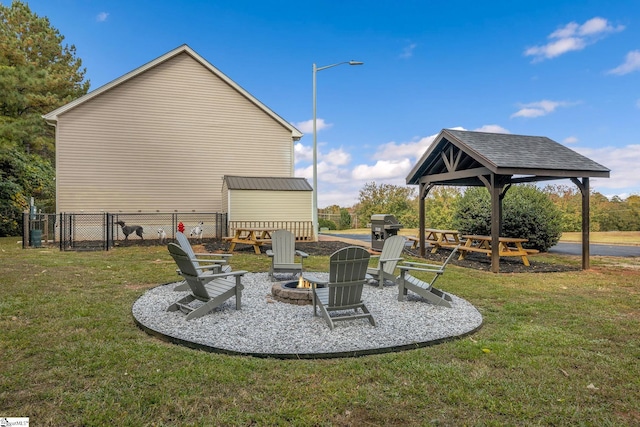 view of yard with a gate, fence, an outdoor structure, a storage unit, and a fire pit