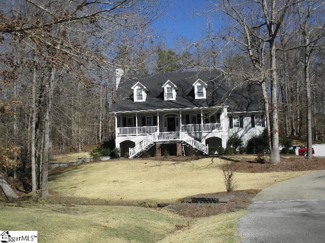 cape cod-style house with stairway, covered porch, and a front yard