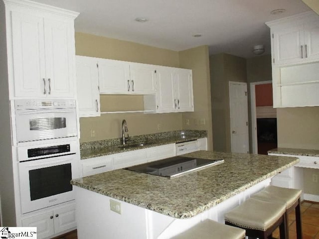 kitchen with white cabinetry, white appliances, a center island, and a sink