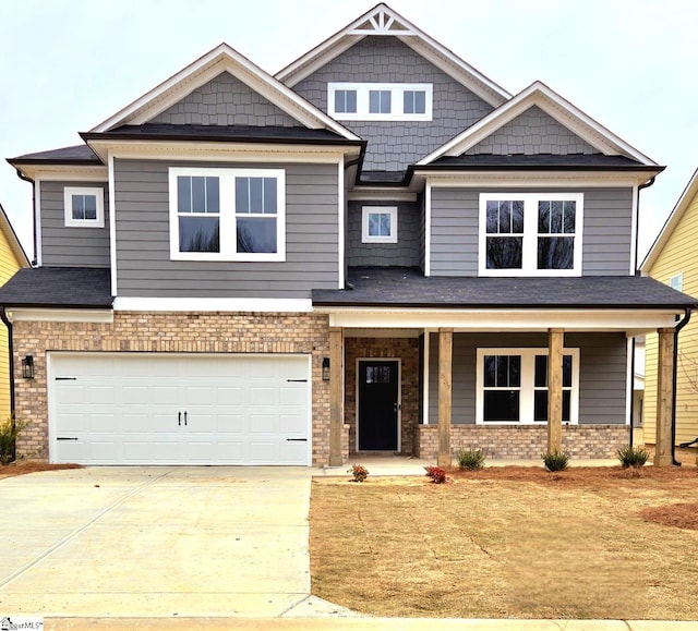 craftsman house with brick siding, covered porch, driveway, and an attached garage