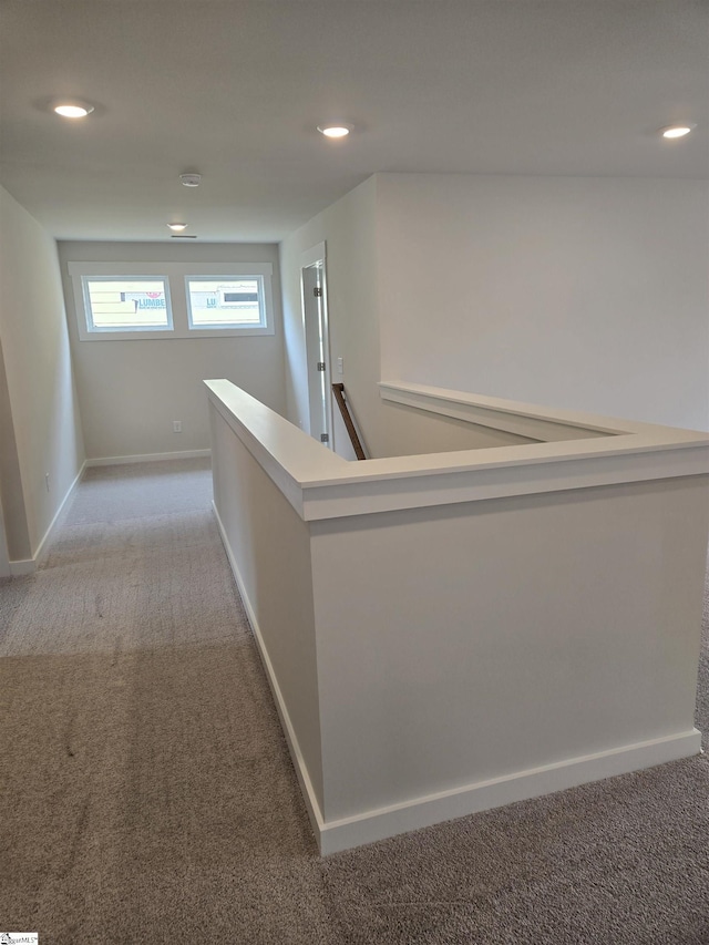 hall with recessed lighting, an upstairs landing, baseboards, and light carpet