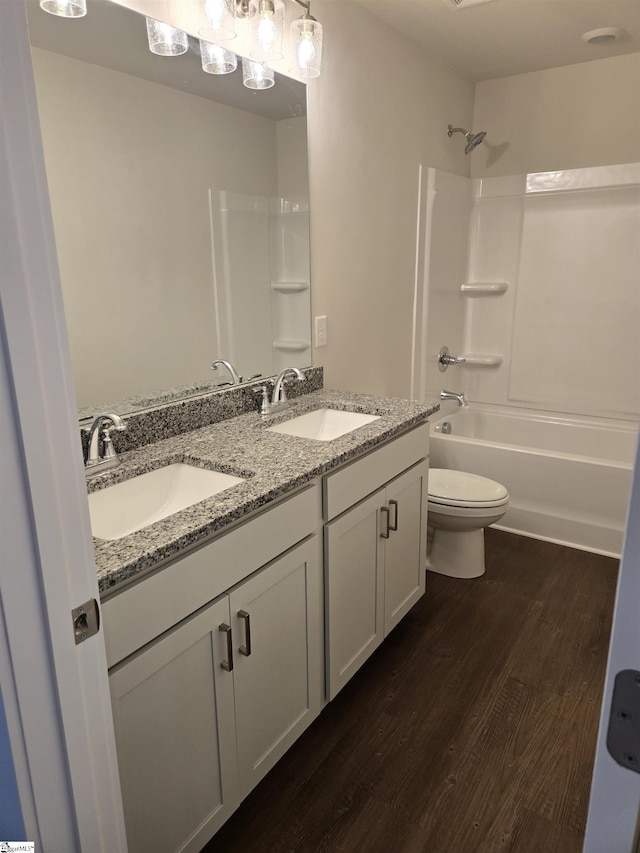 bathroom featuring double vanity, toilet, wood finished floors, and a sink