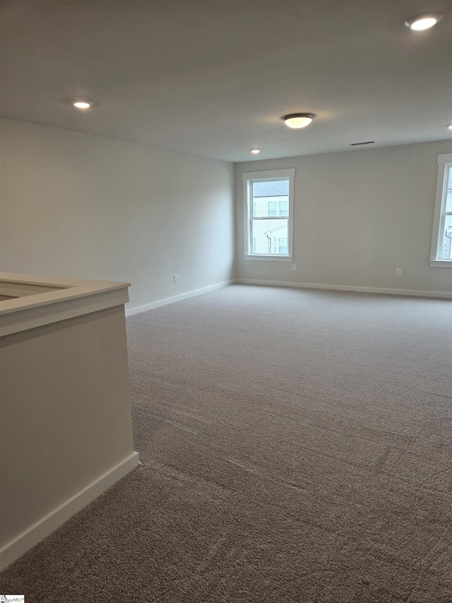 unfurnished room with a wealth of natural light, baseboards, and carpet floors