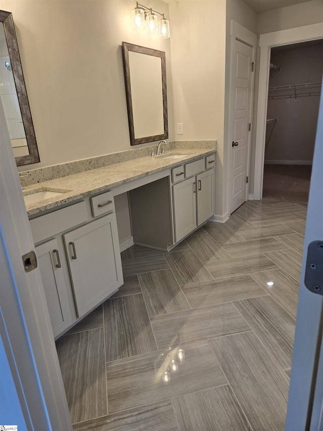 bathroom featuring a walk in closet, double vanity, and a sink