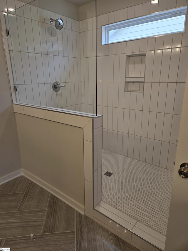 bathroom with a walk in shower and baseboards