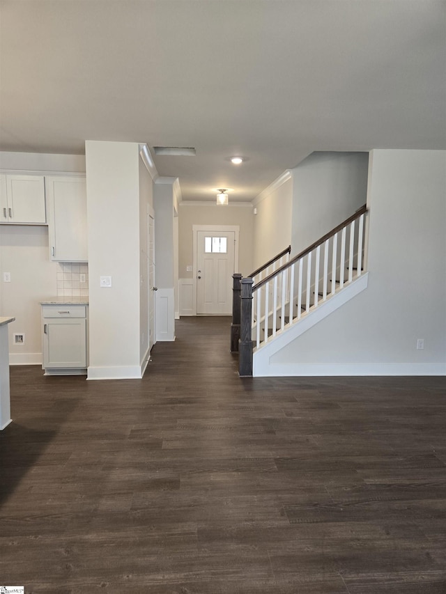 foyer with stairway, baseboards, dark wood finished floors, and ornamental molding