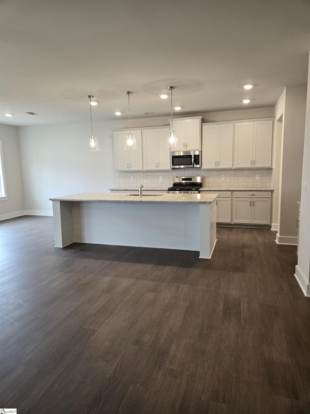 kitchen with dark wood finished floors, a sink, white cabinets, appliances with stainless steel finishes, and backsplash