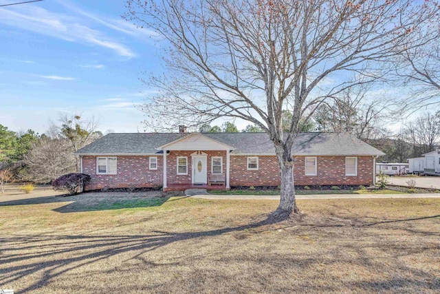 single story home featuring brick siding, a shingled roof, and a front lawn