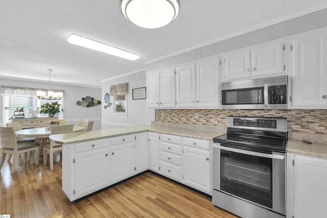 kitchen with ornamental molding, a peninsula, appliances with stainless steel finishes, white cabinets, and light countertops