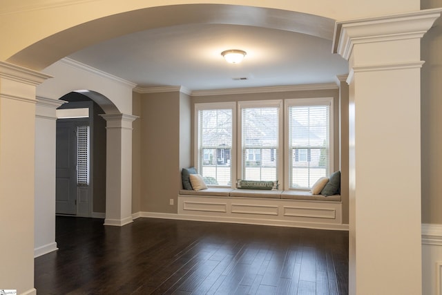 unfurnished room with dark wood finished floors, crown molding, arched walkways, and ornate columns