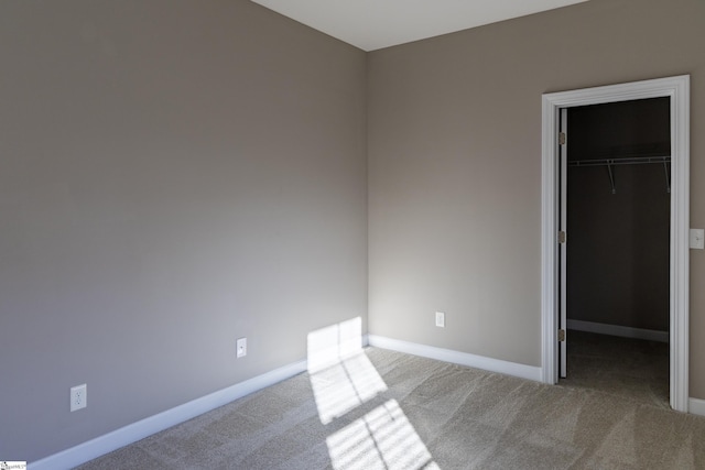 unfurnished bedroom featuring a spacious closet, carpet, baseboards, and a closet