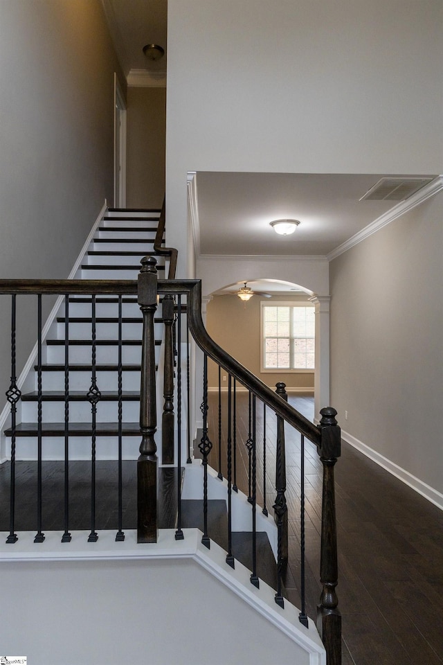 stairs featuring wood finished floors, visible vents, baseboards, arched walkways, and crown molding