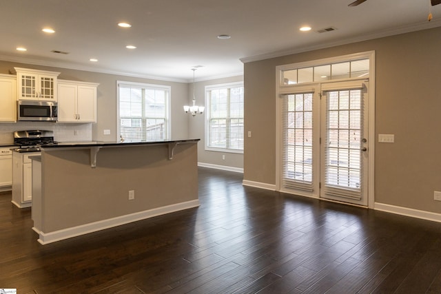 kitchen featuring dark countertops, appliances with stainless steel finishes, ornamental molding, and dark wood-style flooring