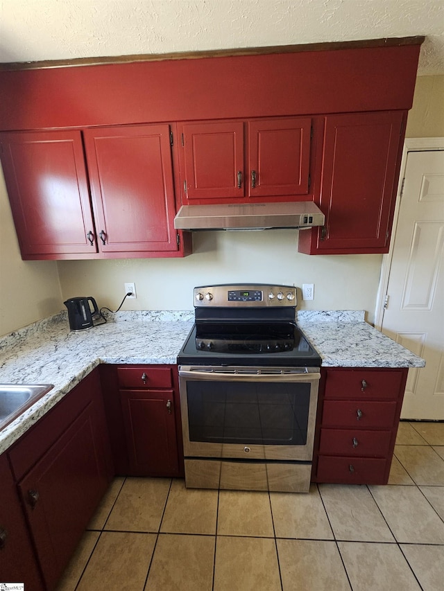 kitchen with electric stove, light tile patterned flooring, under cabinet range hood, and reddish brown cabinets