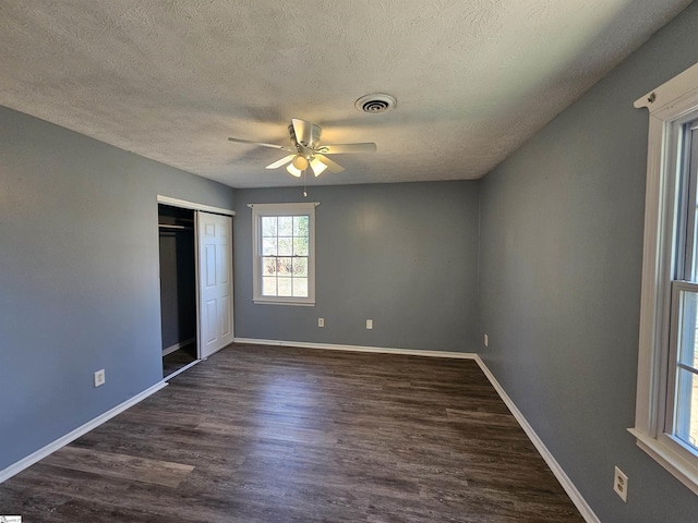 unfurnished bedroom with dark wood-style floors, visible vents, a closet, and baseboards