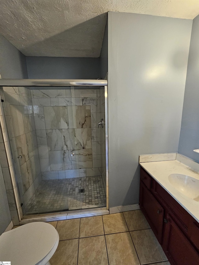 full bath featuring toilet, a stall shower, a textured ceiling, tile patterned flooring, and vanity