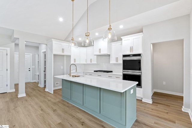 kitchen with double oven, light countertops, decorative backsplash, white cabinets, and a sink