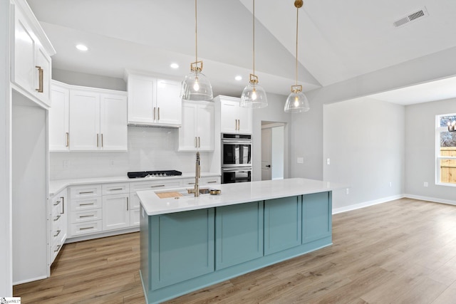 kitchen featuring visible vents, light countertops, light wood-style floors, stainless steel double oven, and gas cooktop