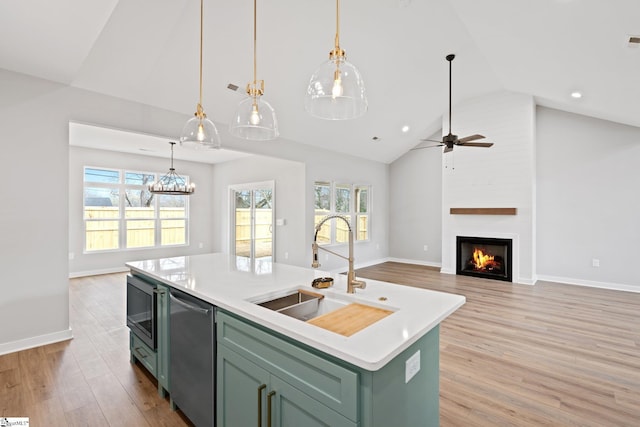 kitchen featuring dishwasher, light wood-style flooring, green cabinets, and a sink