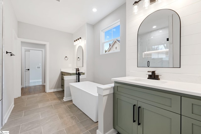 full bath with a freestanding tub, two vanities, a stall shower, a sink, and baseboards