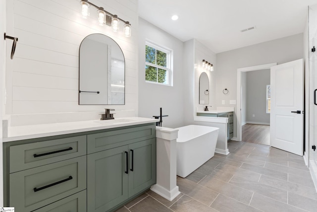 full bath with a sink, visible vents, a freestanding bath, and two vanities