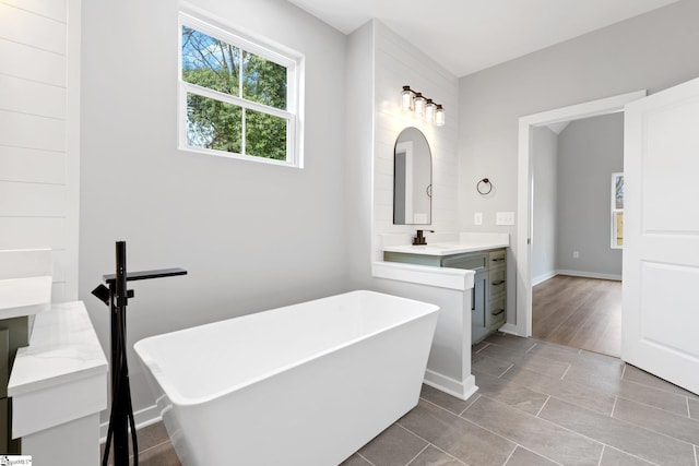 bathroom featuring vanity, a soaking tub, and baseboards