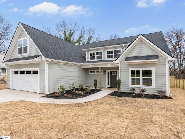 view of front facade with roof with shingles, concrete driveway, a front lawn, and fence