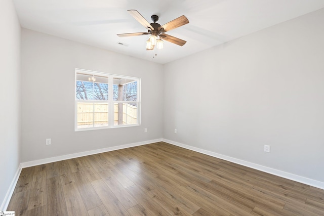 empty room with wood finished floors, visible vents, and baseboards