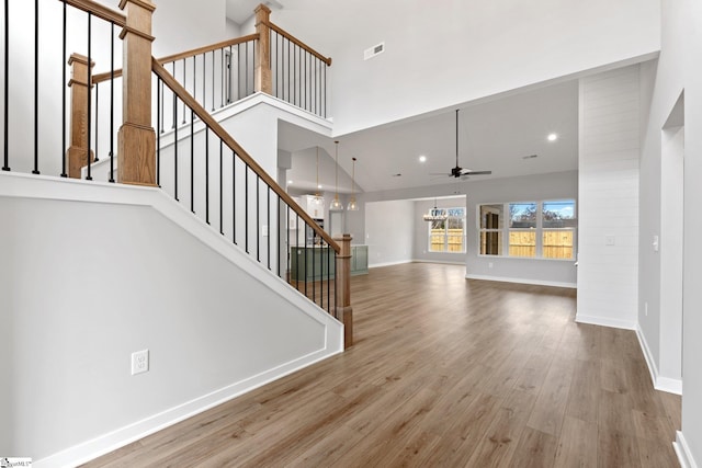 unfurnished living room featuring stairway, wood finished floors, a high ceiling, and baseboards