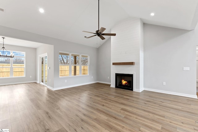 unfurnished living room with visible vents, ceiling fan with notable chandelier, wood finished floors, a large fireplace, and baseboards