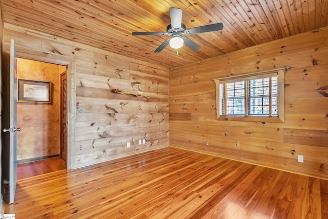 unfurnished room with wood walls, wood ceiling, ceiling fan, and wood-type flooring