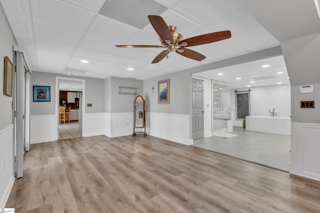 interior space featuring a wainscoted wall, light wood-style flooring, and a barn door