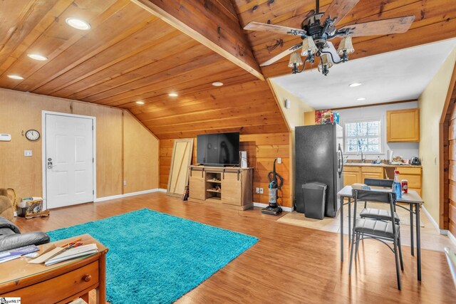 living area with ceiling fan, wood walls, light wood-type flooring, lofted ceiling, and wooden ceiling