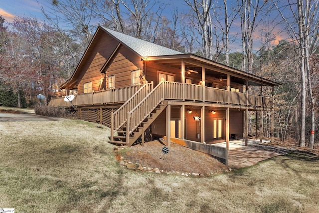 view of front of home with stairway, roof with shingles, ceiling fan, a front lawn, and a deck