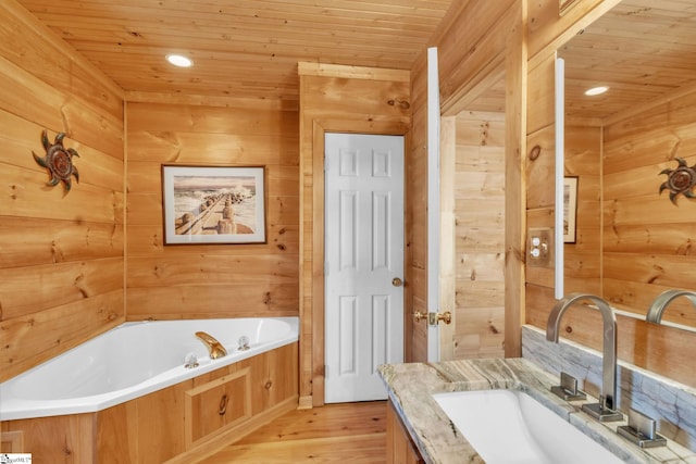 bathroom featuring vanity, wooden walls, a garden tub, wood finished floors, and wooden ceiling