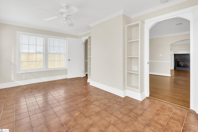 tiled spare room featuring built in features, a fireplace, arched walkways, and baseboards