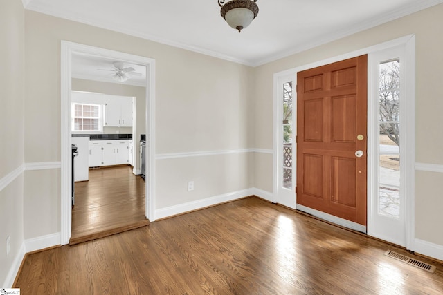 foyer featuring visible vents, ornamental molding, baseboards, and wood finished floors