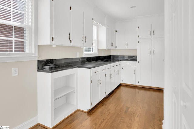 kitchen featuring dark countertops, light wood finished floors, ornamental molding, white cabinetry, and open shelves