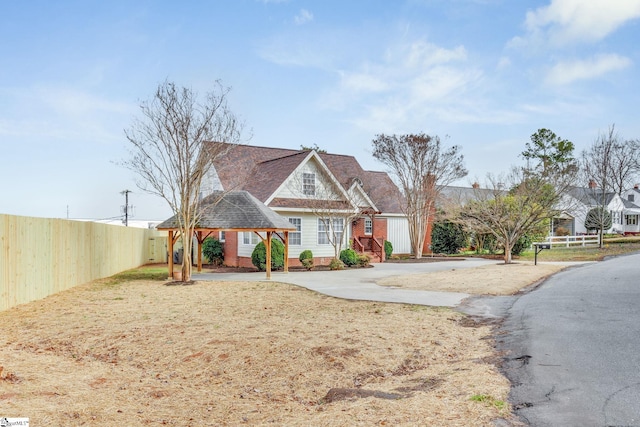 view of front of home featuring concrete driveway, fence, and brick siding