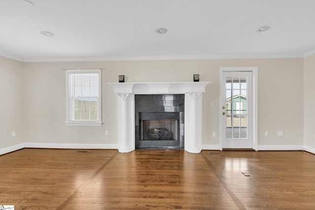 unfurnished living room with baseboards, a healthy amount of sunlight, wood finished floors, and a tiled fireplace