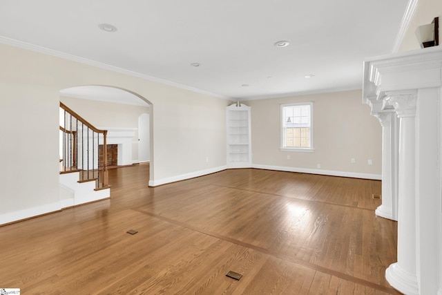 unfurnished living room with baseboards, wood finished floors, and crown molding