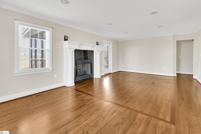 unfurnished living room with visible vents, crown molding, baseboards, hardwood / wood-style floors, and a fireplace