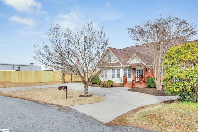 view of front of house with brick siding, driveway, and fence