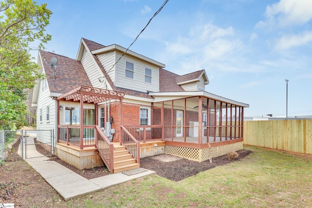 rear view of property with brick siding, a wooden deck, a lawn, a fenced backyard, and a gate